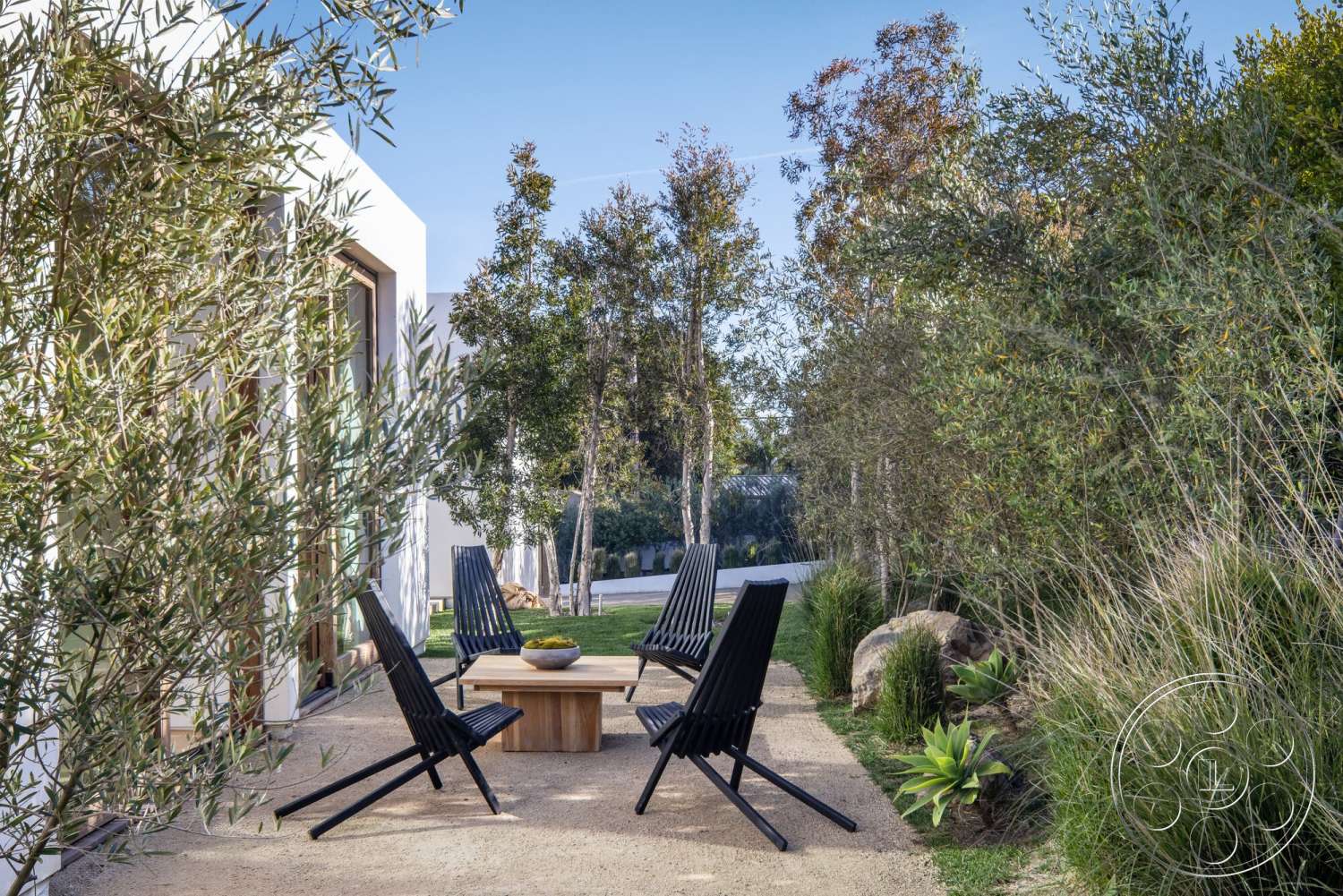 Modern 529 - exterior, minimalist design, open space layout, deciduous trees, ornamental grasses, concrete patio flooring, landscaped garden setting, modern outdoor seating area, wooden outdoor coffee table, black metal lounge chairs