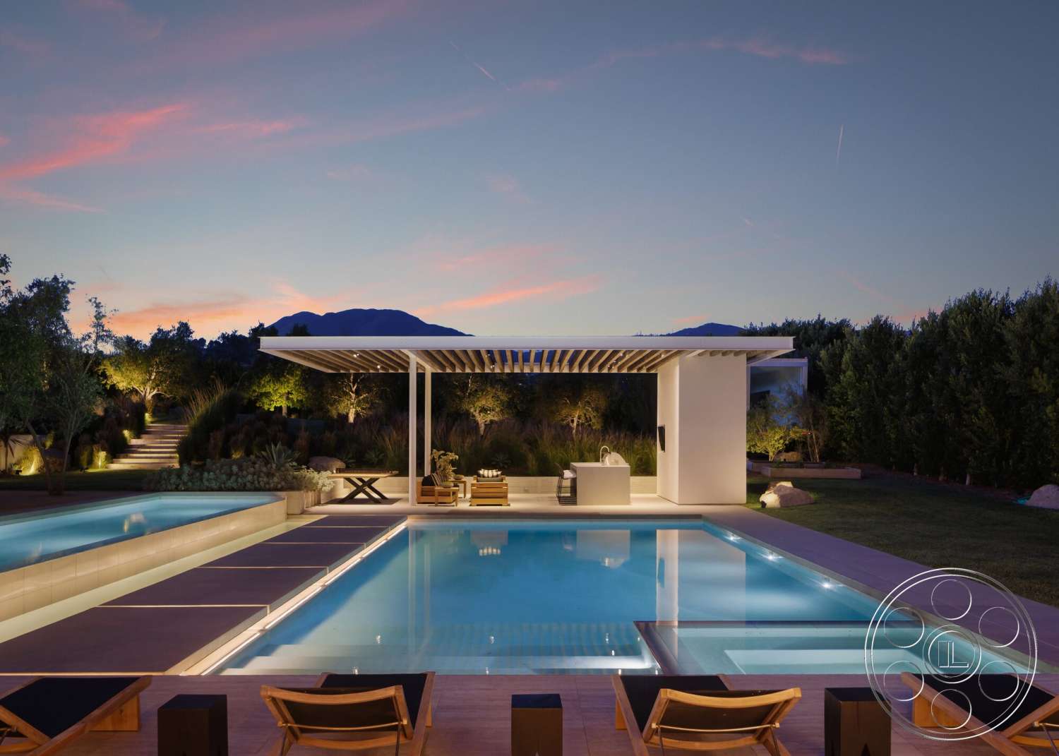 Modern 529 - exterior, lush greenery, rectangular swimming pool, contemporary design elements, mountain backdrop, wooden lounge chairs, concrete patio floor, softscape landscaping, modern outdoor setting, light-colored stone pool decking, white trellis patio cover, nighttime outdoor lighting, custom outdoor kitchen