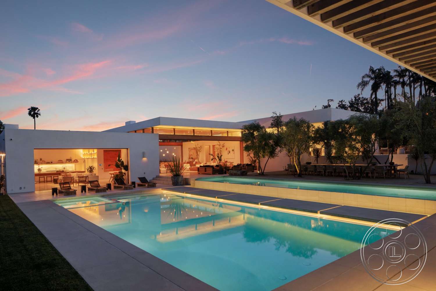 Modern 529 - exterior, landscaped garden, white stucco walls, glass sliding doors, modern outdoor furniture, rectangular swimming pool, floor-to-ceiling windows, concrete pool deck, wood ceiling beams, chef's kitchen, surrounding palm trees, contemporary architectural style, open concept kitchen, concrete patio floor, evening sky, illuminated pool edge, dining area next to pool