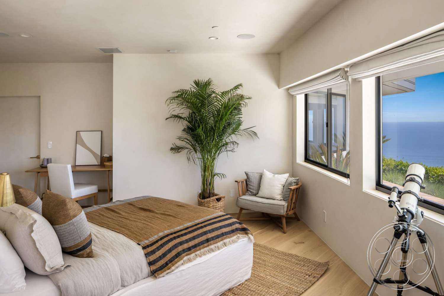 Modern 528 - light wood flooring, floor-to-ceiling windows, artwork on wall, textured throw blanket, master bedroom, plaster wall finish, modern accent chair, minimalist desk with chair, striped decorative pillows, decorative potted palm