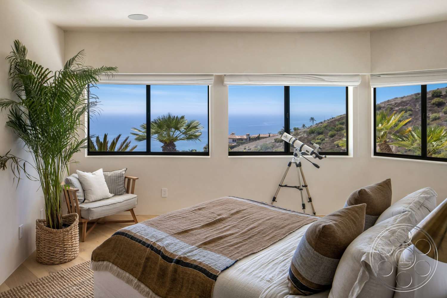 Modern 528 - floor-to-ceiling windows, woven area rug, textured plaster walls, coastal landscape, modern armchair, light hardwood bedroom floors, neutral bedding with decorative pillows, outdoor view with palm trees, telescope