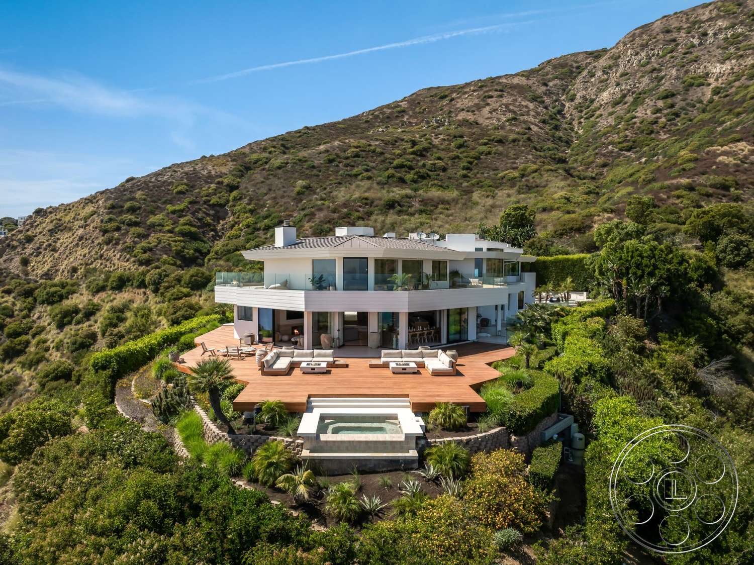Modern 528 - flat roof, large glass windows, natural landscaping, outdoor lounge area, modern exterior, mountain view, stucco walls, infinity pool, hillside location, open-concept design, floor-to-ceiling glass doors, stone retaining walls, wraparound wooden deck, concrete spa surround
