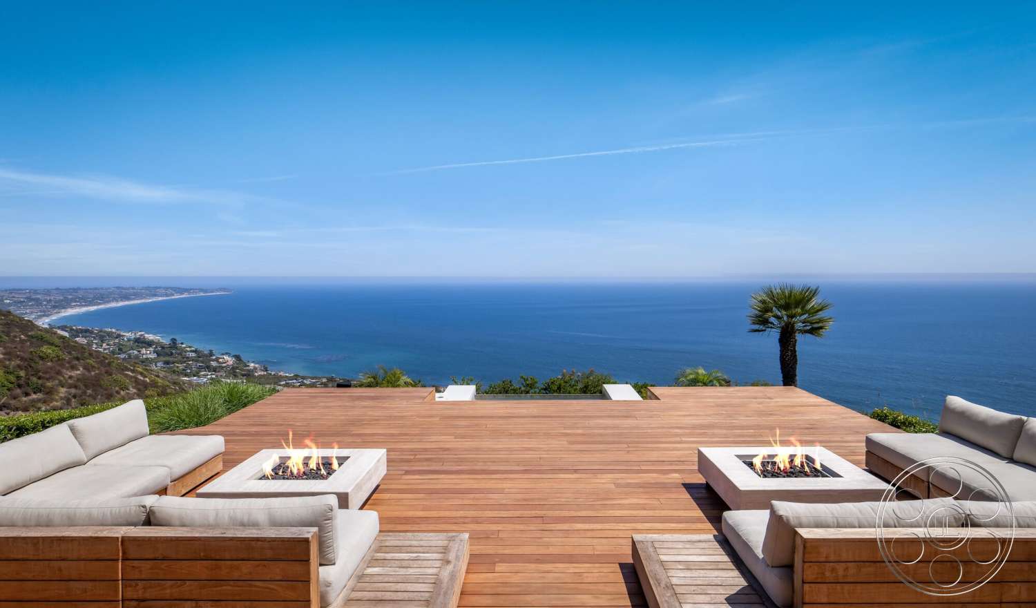 Modern 528 - exterior, contemporary design elements, modern outdoor seating, minimalist outdoor space, palm tree landscaping, rectangular fire pit, landscaped hillside setting, coastal ocean view, open sky backdrop, timber deck flooring