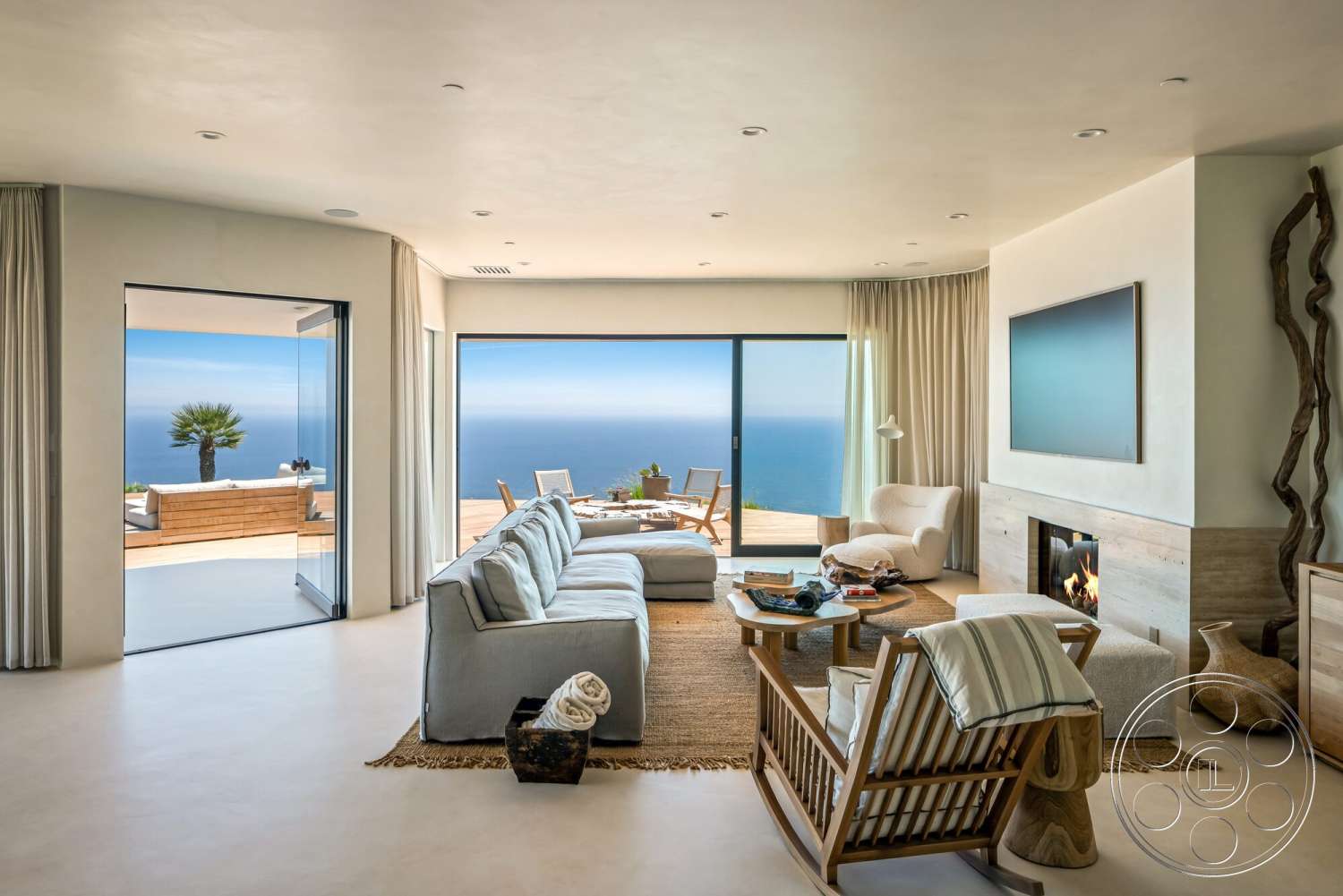 Modern 528 - minimalist decor, neutral color palette, textured area rug, open floor plan, curtains, concrete floor, sliding glass doors, modern coffee table, floor-to-ceiling windows, lounge area, wooden accent chair, coastal view, light-colored plaster walls, built-in fireplace with stone surround
