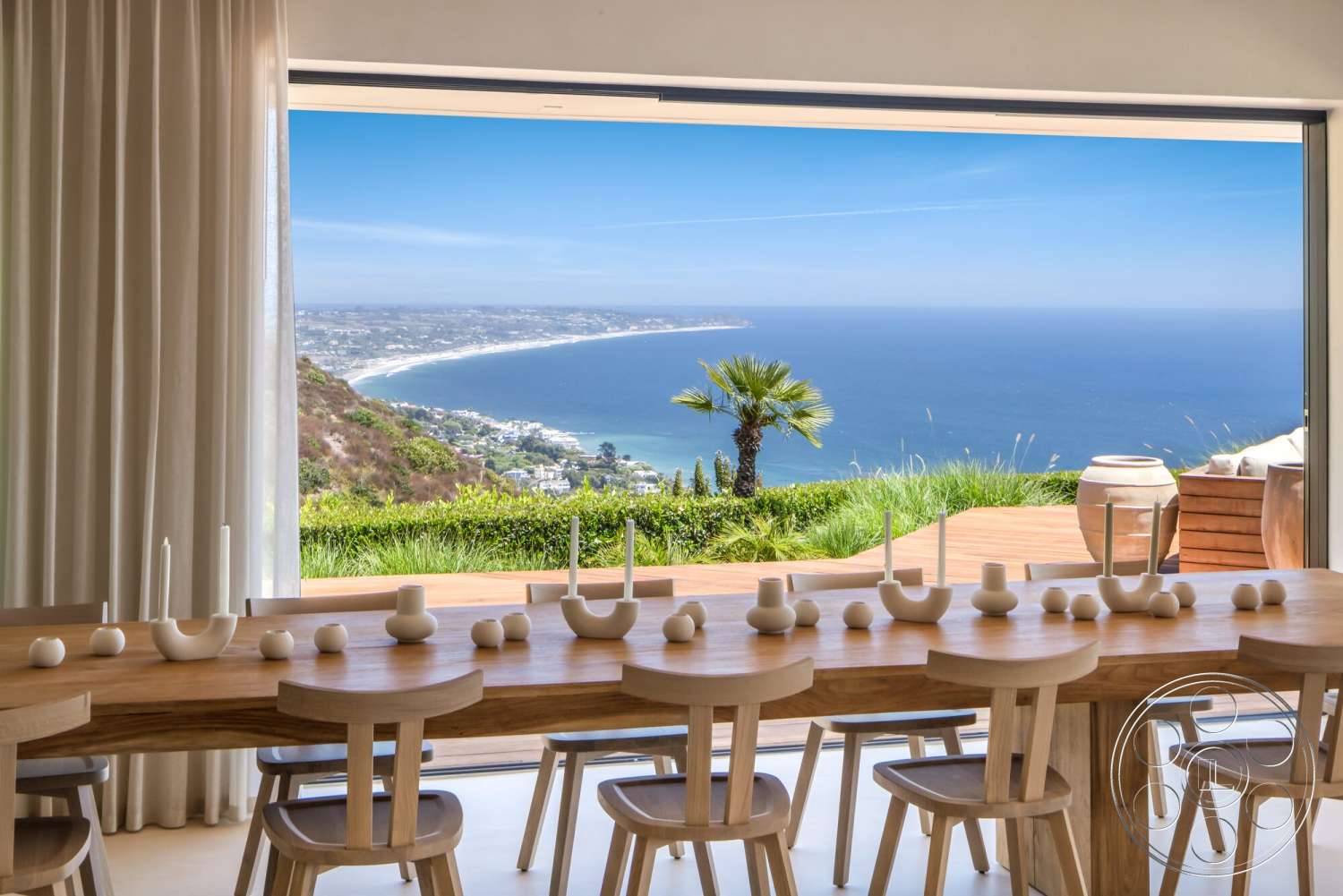 Modern 528 - white walls, minimalist decor, natural light, open floor plan, wood dining table, ocean view, sheer white curtains, contemporary architectural style, interior dining area, floor-to-ceiling glass doors, landscape with palm trees, light wood dining chairs, connected indoor and outdoor spaces