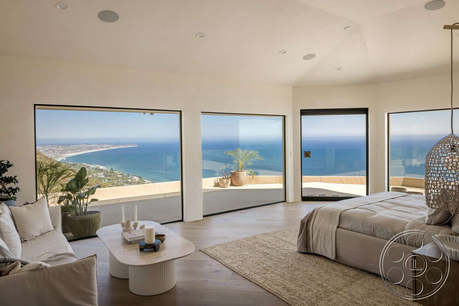 Modern 528 - modern architecture, floor-to-ceiling windows, ocean view, minimalist coffee table, beige area rug, coastal setting, woven pendant light fixture, hardwood bedroom floors, white painted walls, rounded ceiling shape, curved window openings, plant in decorative pot