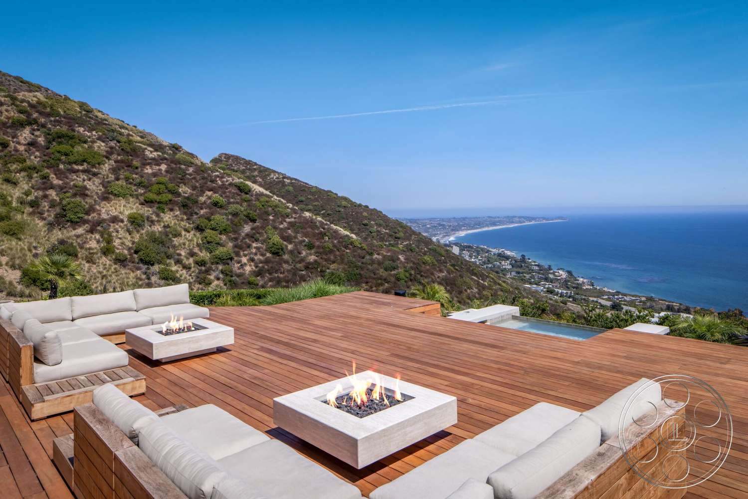 Modern 528 - exterior, open outdoor space, mountain view, coastal landscape, contemporary outdoor design, panoramic ocean view, wood deck flooring, infinity pool edge, modular outdoor sectional sofa, fire pit with concrete surround, natural stone hillside