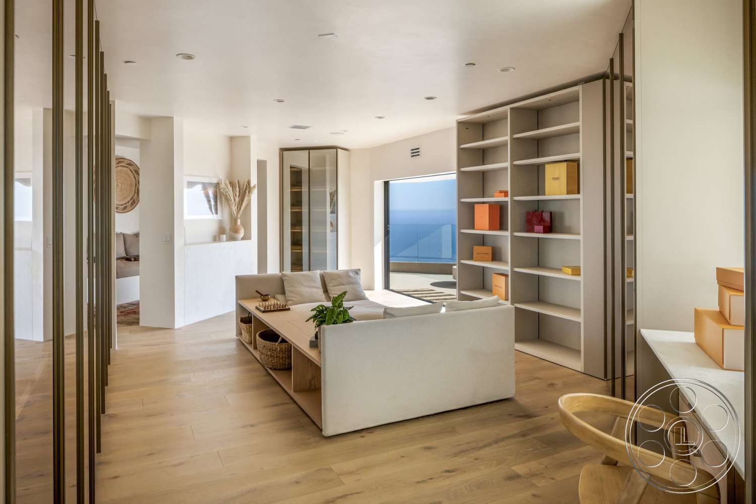Modern 528 - neutral color palette, light hardwood flooring, open concept living space, glass sliding door, minimalist furniture design, large windows with ocean view, potted plants as decor, exposed plaster walls, contemporary shelving units, decorative woven wall art