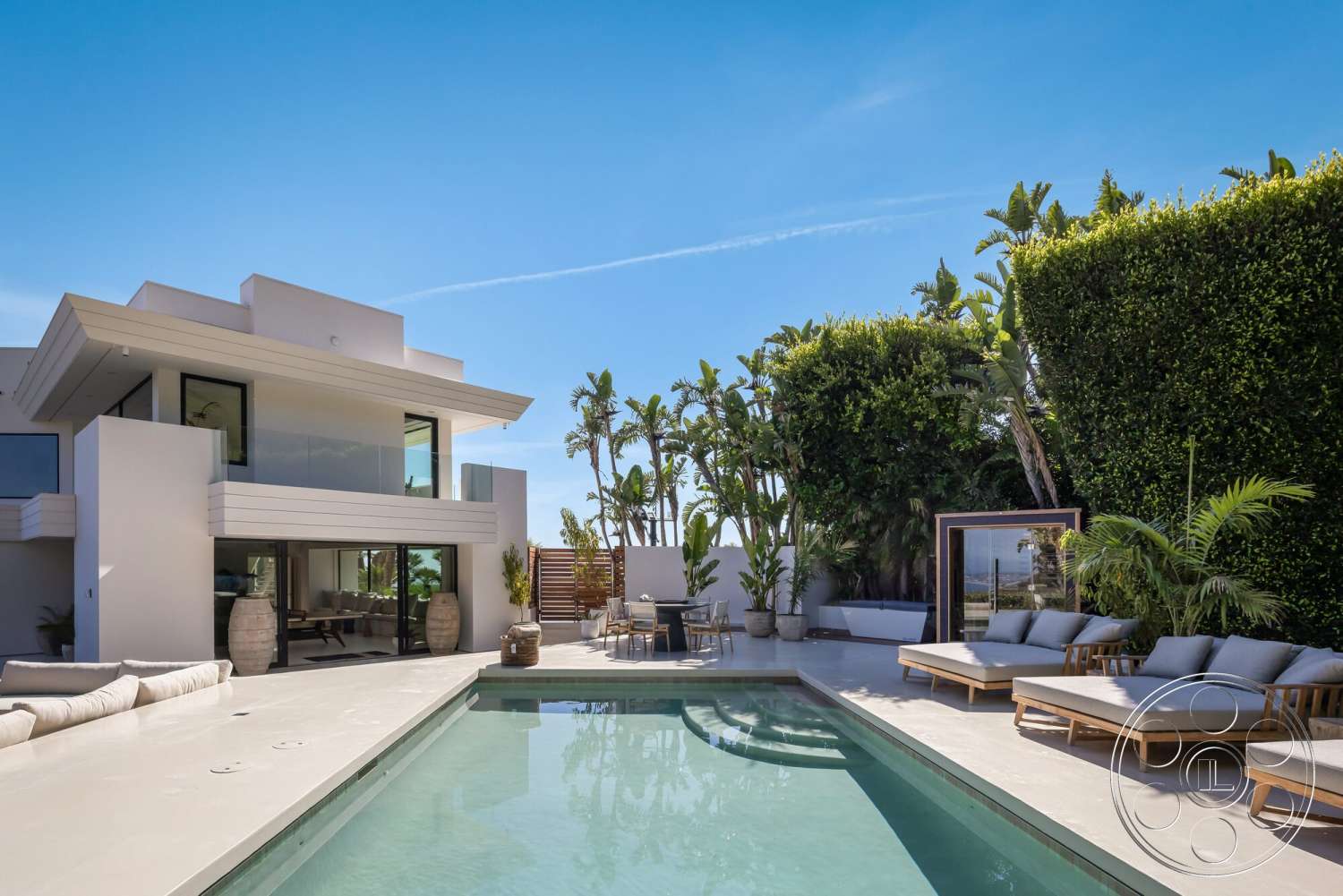 Modern 528 - exterior, white stucco walls, sliding glass doors, floor-to-ceiling windows, modern architectural style, tropical landscaping, concrete pool deck, rectangular pool, large potted plants, wooden lounge chairs, flat roof design, glass patio enclosure
