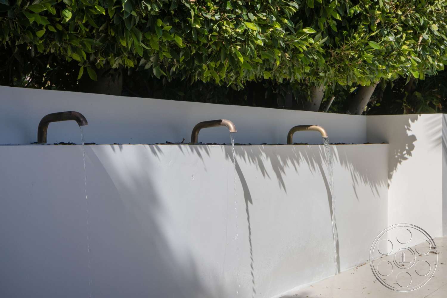 Modern 528 - exterior, minimalist design elements, textured concrete surface, smooth concrete base, concrete water feature wall, copper faucets, water spouts, green foliage background