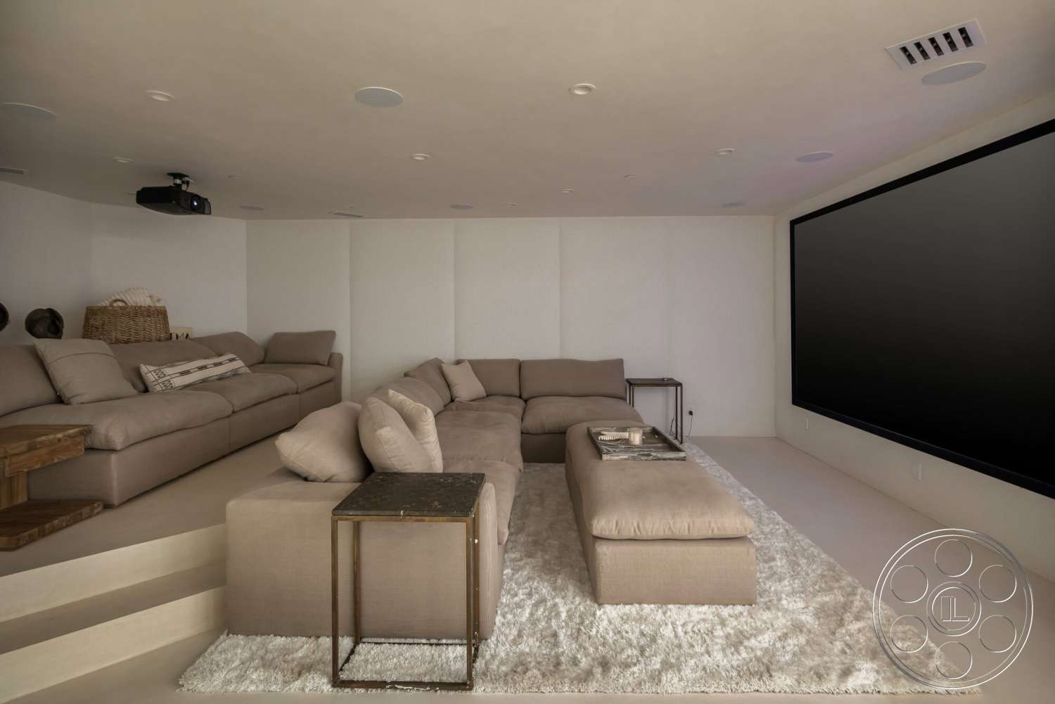 Modern 528 - neutral color palette, textured plaster walls, wood accent table, recessed ceiling lighting, fabric sectional sofa, soft rug flooring, built-in projector, floor-to-ceiling screen, cozy media room