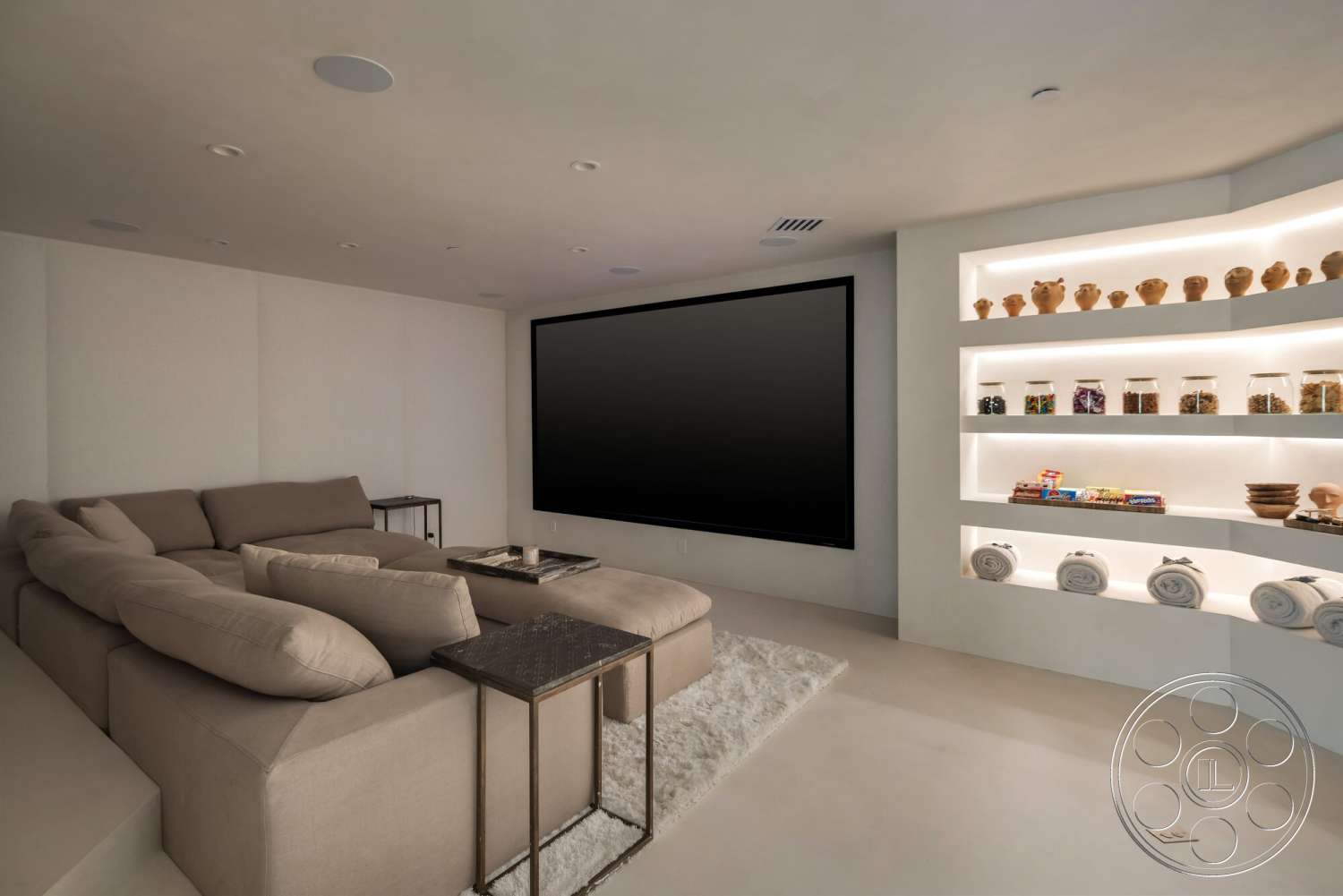 Modern 528 - recessed lighting, concrete flooring, open concept layout, black flat-screen television, built-in shelving unit, decorative ceramic vases, light-colored plaster walls, illuminated display shelves, tufted beige sectional sofa, minimalist corner side table, low-profile coffee table, textured white area rug