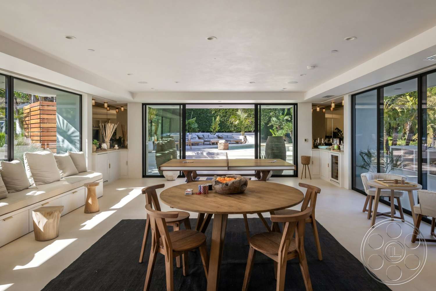 Modern 528 - minimalist decor, natural light, light-colored walls, open floor plan, soft textiles, concrete flooring, large glass doors, floor-to-ceiling windows, contemporary furnishings, outdoor pool view, wooden dining chairs, round wooden dining table, exposed ceiling lights, modern living room, custom built-in seating