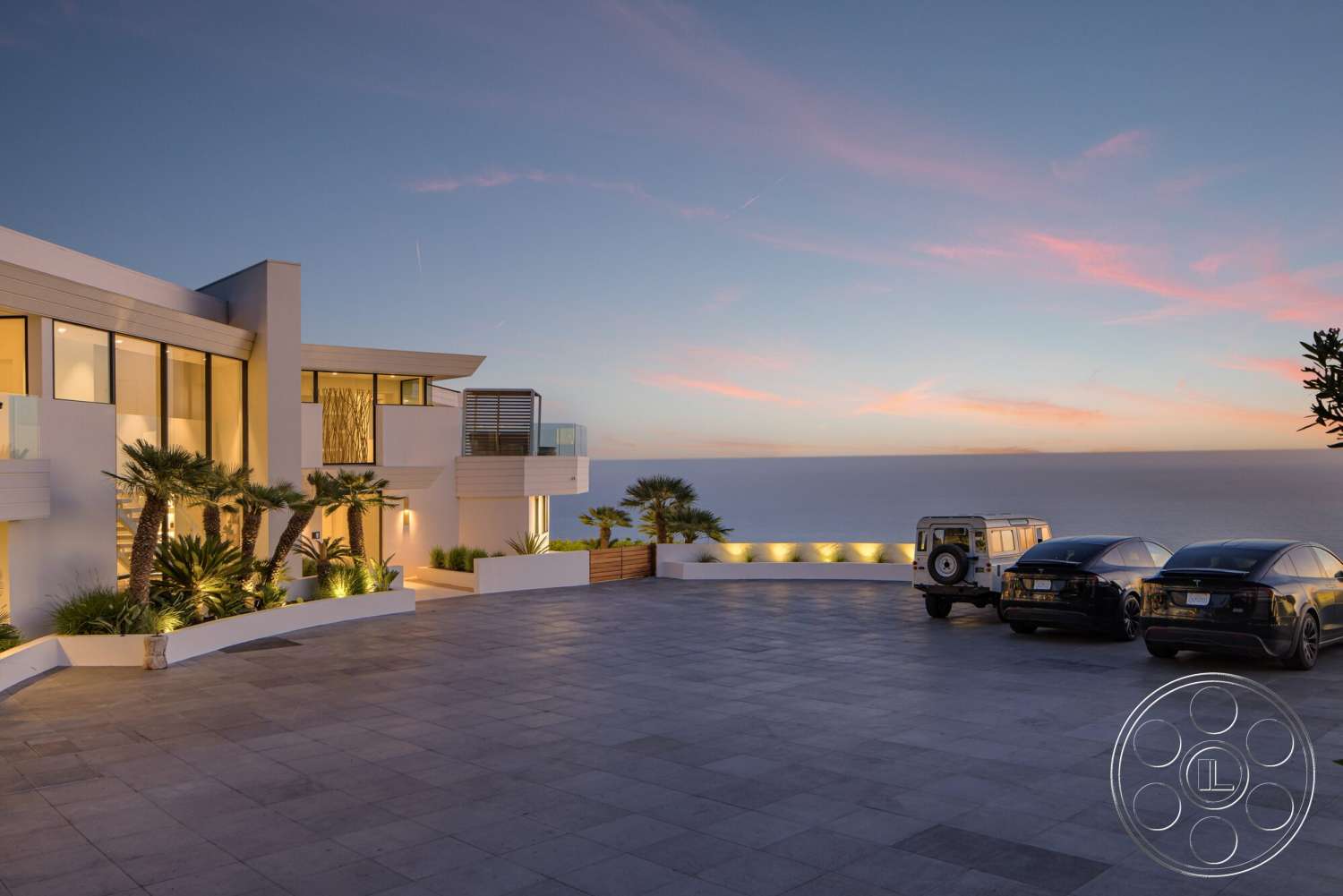 Modern 528 - exterior, modern architecture, minimalist design, outdoor seating area, glass windows, sloped roof, concrete driveway, large patio area, stucco exterior walls, landscaped with palm trees, metal balcony railing, illuminated outdoor lighting, open sea view, rectangular swimming pool area
