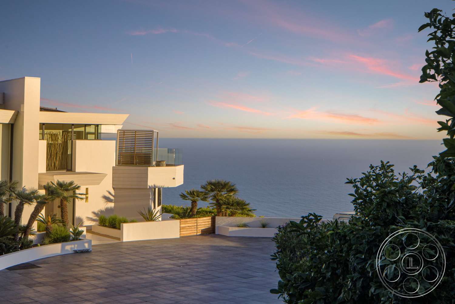 Modern 528 - exterior, white stucco walls, flat roof, ocean view, tropical landscaping, large floor-to-ceiling windows, contemporary architectural style, stone patio flooring, glass balcony railings, rectangular patio, modern outdoor living space
