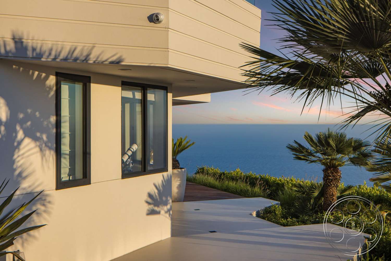 Modern 528 - exterior, palm trees, wooden decking, concrete pathway, tropical landscaping, panoramic ocean view, modern architectural design, large black-framed windows, suburban hillside location, smooth white stucco walls, flat roofline, deck with ocean view