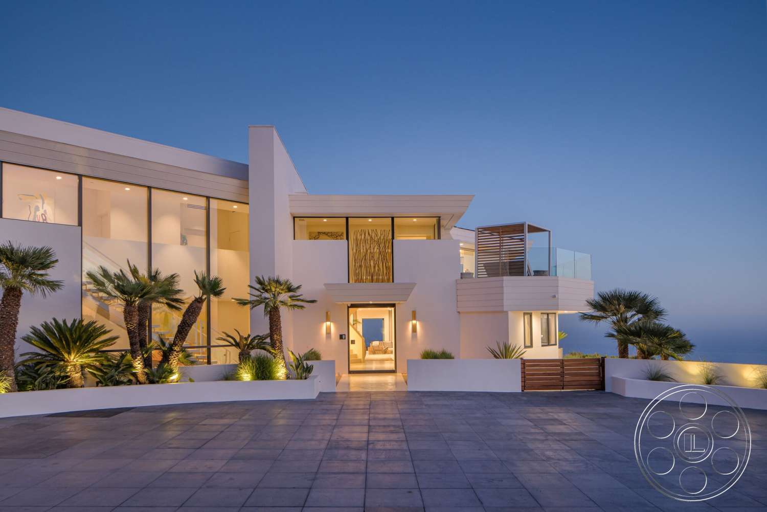 Modern 528 - exterior, white stucco walls, modern architectural style, open-air design, concrete driveway, sea view, outdoor patio space, integrated outdoor lighting, flat roof design, landscaped garden with palm trees, glass panel windows, horizontal wood slat accents, large front entrance door, curved concrete wall