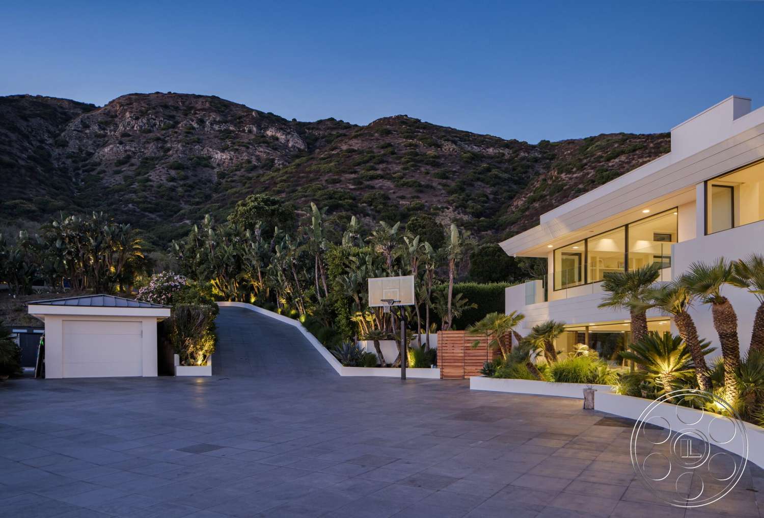 Modern 528 - exterior, landscaped garden, flat roof, palm trees, floor-to-ceiling windows, modern architectural style, concrete driveway, sloped driveway, concrete retaining wall, paved patio area, exterior lighting features, surrounding mountain view, stucco wall finishes, built-in basketball hoop