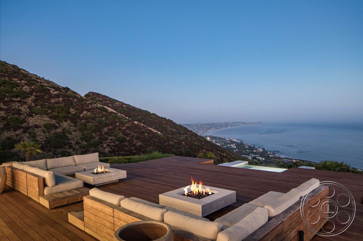 Modern 528 - exterior, minimalist design elements, modern outdoor furniture, ocean view, sloped landscape, concrete fire pit, wood deck flooring, coastal hillside setting, wraparound deck