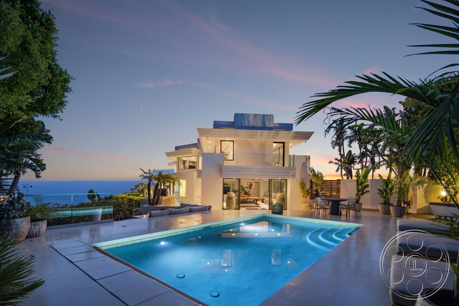 Modern 528 - exterior, white stucco walls, outdoor seating area, glass railing, floor-to-ceiling windows, sunset backdrop, modern architectural style, concrete pool deck, rectangular pool, flat roof design, open patio space, landscaped garden with tropical plants