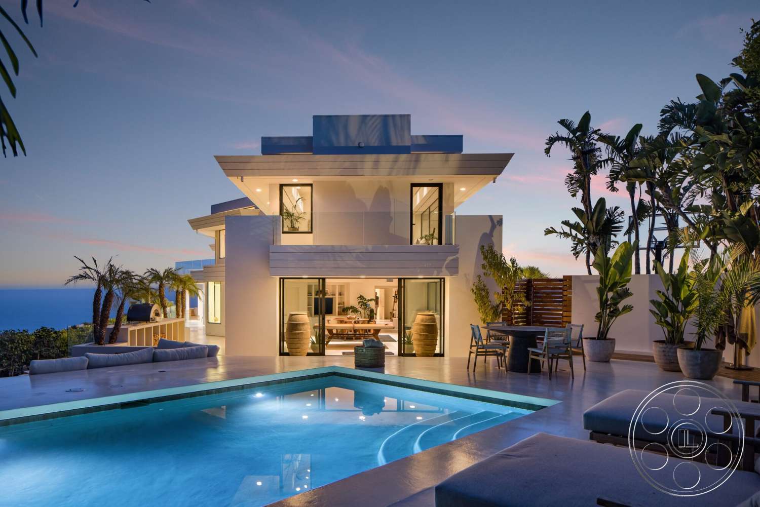 Modern 528 - exterior, white stucco walls, outdoor seating area, floor-to-ceiling windows, concrete pool deck, rectangular pool, flat roof design, potted tropical plants, two-story modern home, ocean view setting, wooden patio dining set