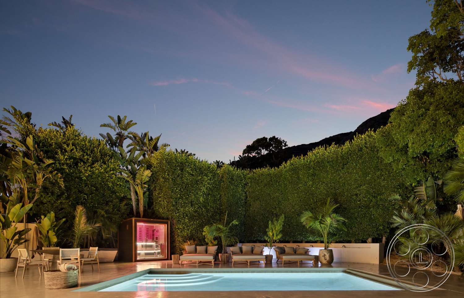 Modern 528 - exterior, modern outdoor furniture, nighttime setting, rectangular pool, stone pool deck, soft lighting ambiance, concrete pool patio, potted tropical plants, lush green backdrop, landscaped garden with tall hedges, glass wall sauna structure, contemporary pool area