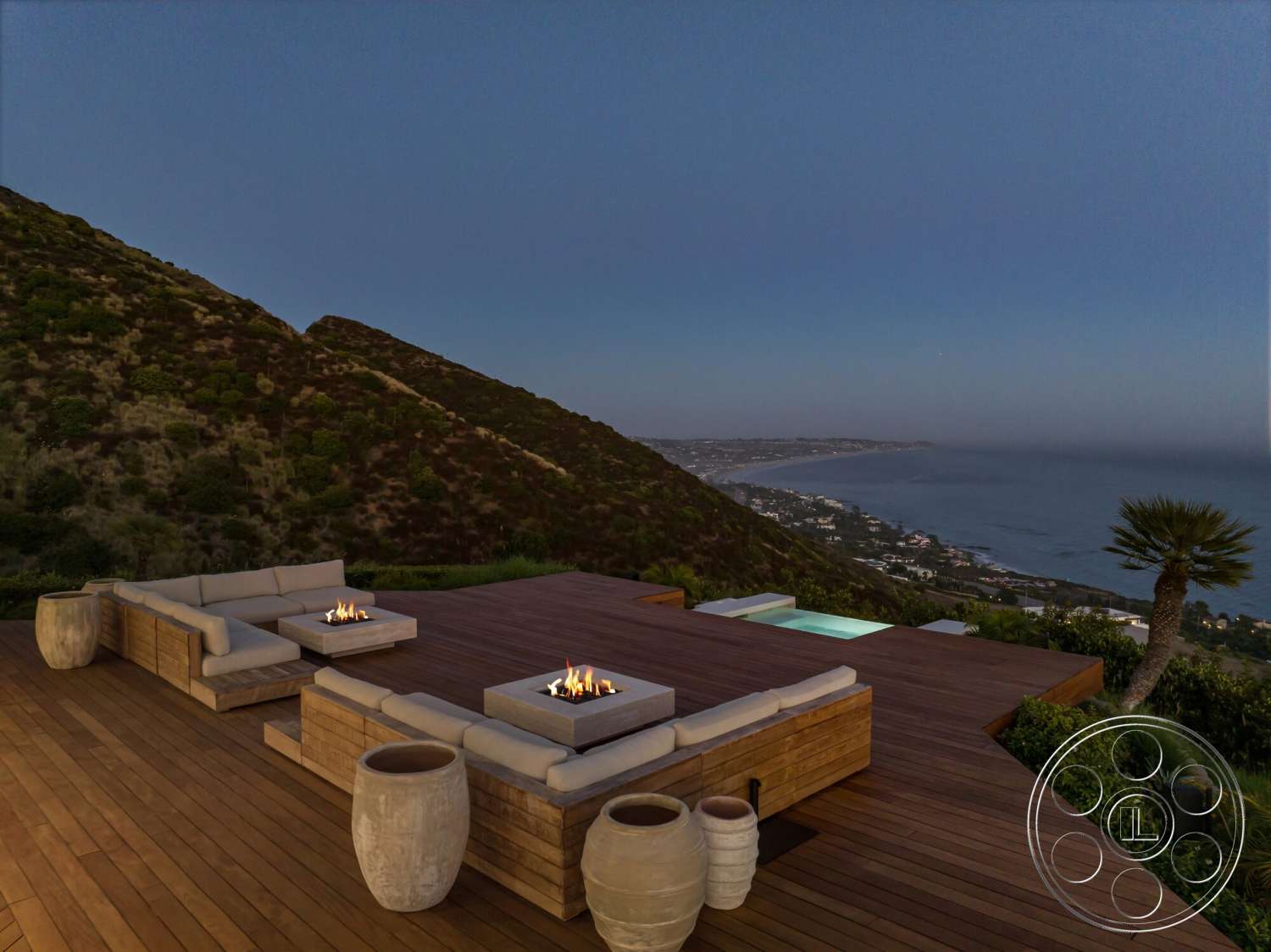 Modern 528 - exterior, pool area, modern lounge area, mountain view setting, contemporary outdoor seating area, wood deck flooring, soft outdoor lighting, oceanfront property, round stone planters, fire pit table with flames, landscape with gentle slopes, expansive decking space