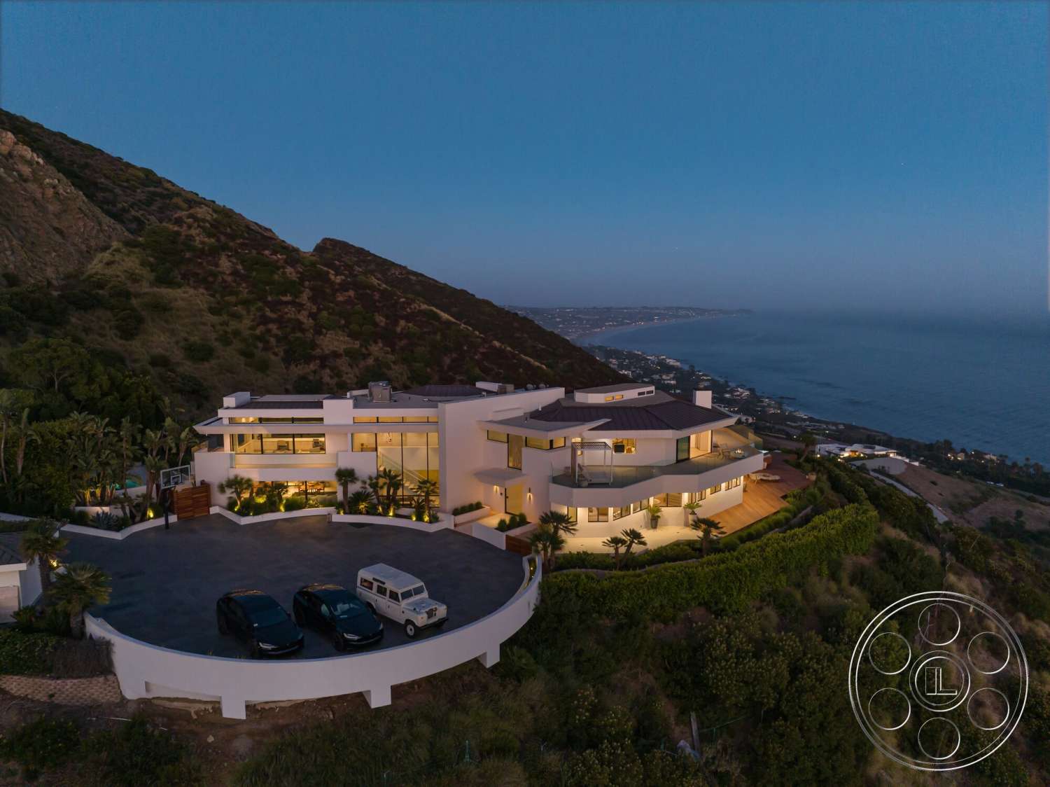 Modern 528 - exterior, white stucco walls, modern architecture, surrounding greenery, glass windows, curved driveway, deck area, hillside property, stone landscaping, flat roof design, panoramic sea view, paved parking area, oceanfront location