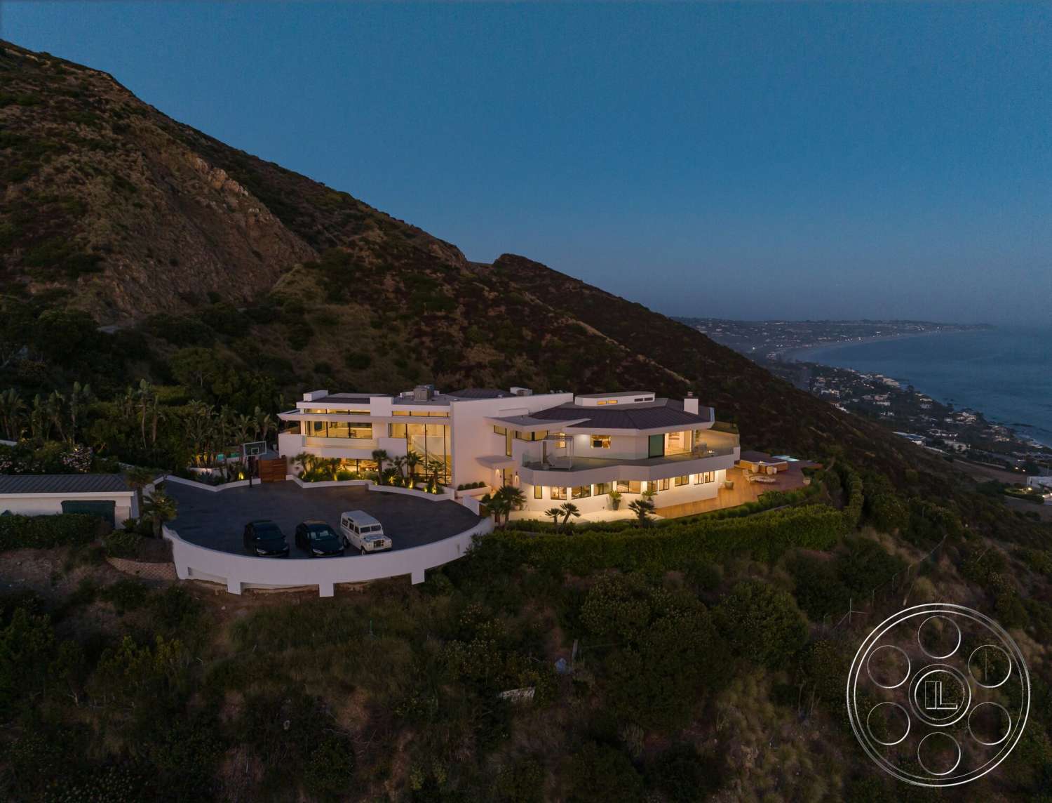 Modern 528 - exterior, landscaped garden, floor-to-ceiling windows, mountain backdrop, outdoor living area, modern residential architecture, two-story home, flat roof design, concrete foundation, glass balcony railing, oceanview setting, paved circular driveway, terraced hillside