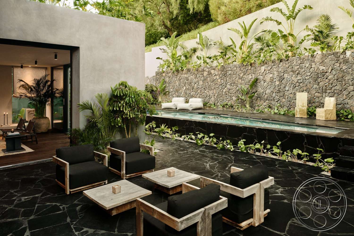 Modern 530 - exterior, sliding glass doors, concrete walls, tropical landscaping, dark wood deck, rectangular pool, natural stone feature wall, modern outdoor living space, flagstone patio flooring, metal frame outdoor seating