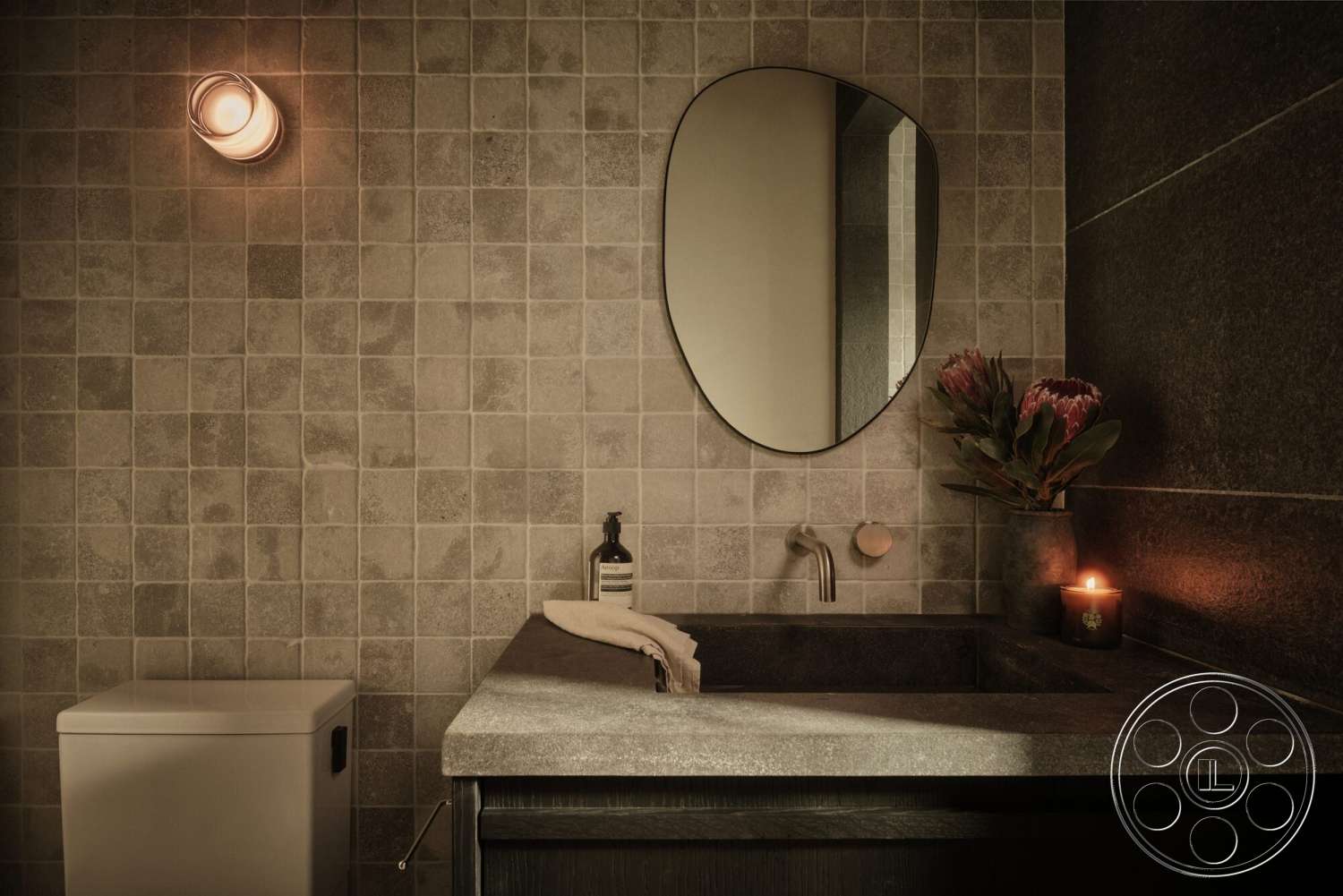Modern 530 - oval mirror, textured plaster walls, dark wood vanity, dark stone countertop, modern wall sconce, white ceramic toilet, mosaic tile bathroom walls