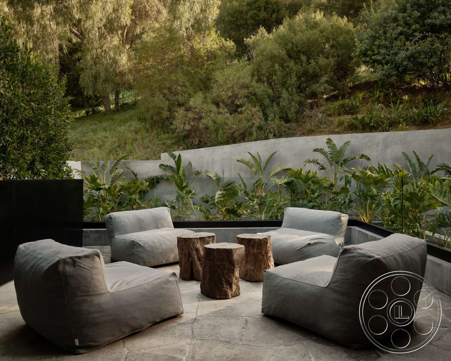 Modern 530 - exterior, outdoor seating area, modern landscaping, concrete wall, textured wall treatment, lush greenery backdrop, stone patio flooring, tropical plant setting, chunky wood side tables, plush fabric lounge chairs