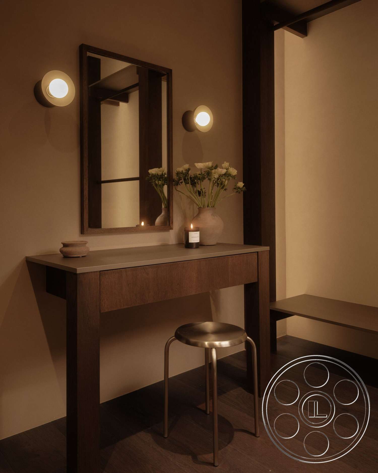Modern 530 - hardwood flooring, metal stool, dark wood paneling, metal wall sconces, mirror with wooden frame, ceramic candle holder, light beige plaster walls, wood vanity with concrete countertop, vase with white flowers, floating shelf under mirror