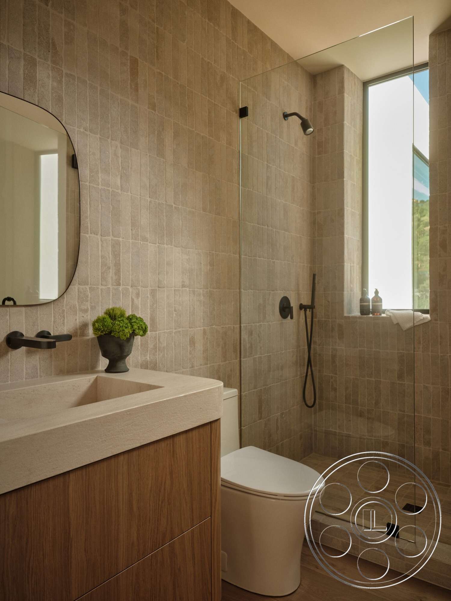 Modern 531 - neutral color palette, glass shower enclosure, oval mirror, natural light window, wood vanity cabinet, wood plank flooring, wall-mounted black faucet, textured stone bathroom walls, solid surface countertop, modern freestanding toilet, minimalist shower head