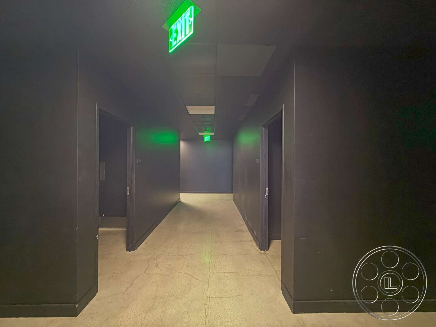 Wilshire Penthouse - polished concrete flooring, horizontal layout, dark painted walls, interior hallway, ceiling tiles, black door frames, green exit sign
