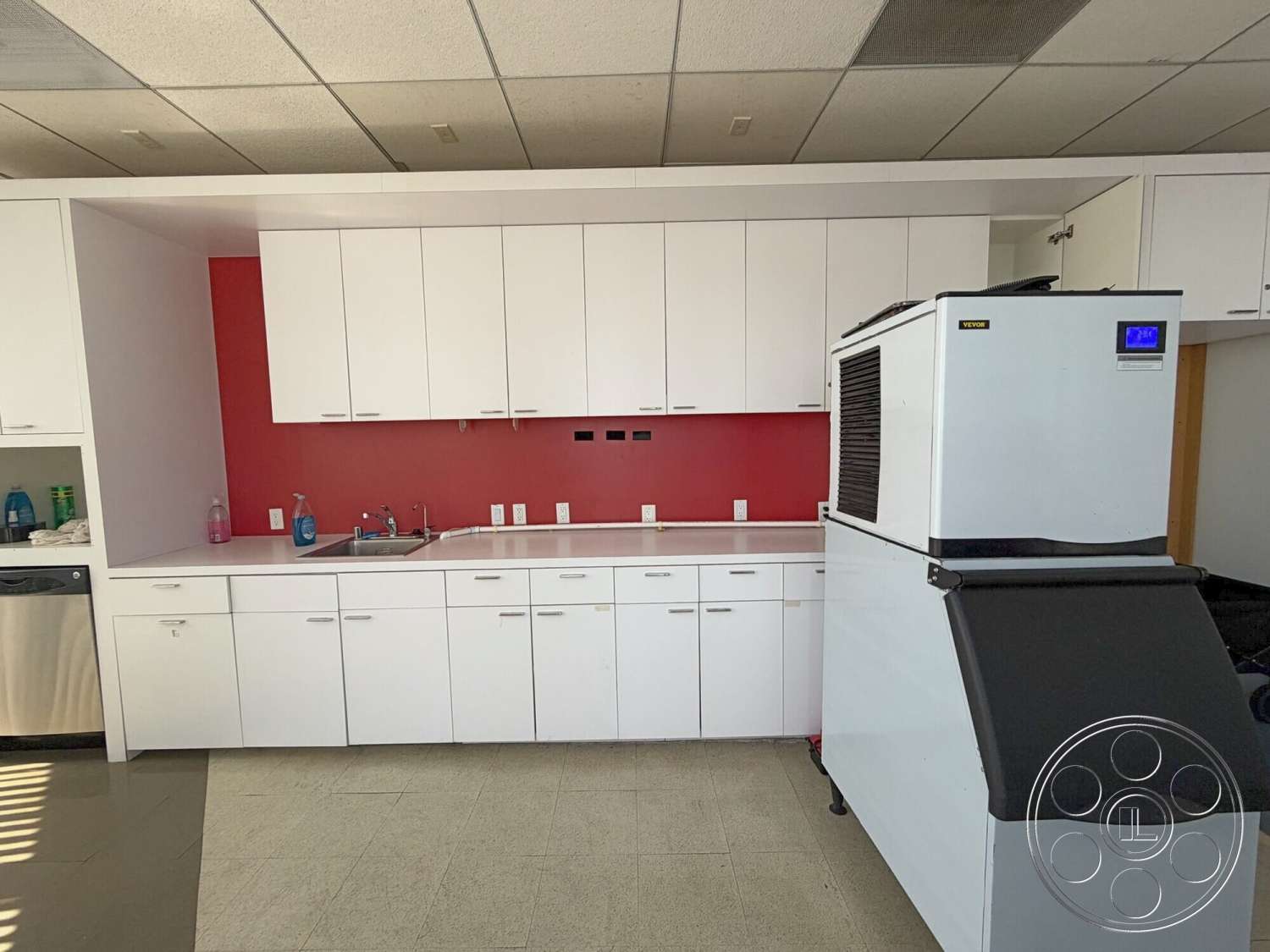 Wilshire Penthouse - red accent wall, stainless steel sink, white quartz countertop, modern kitchen design, white laminate kitchen cabinets, tile kitchen flooring, black commercial ice machine