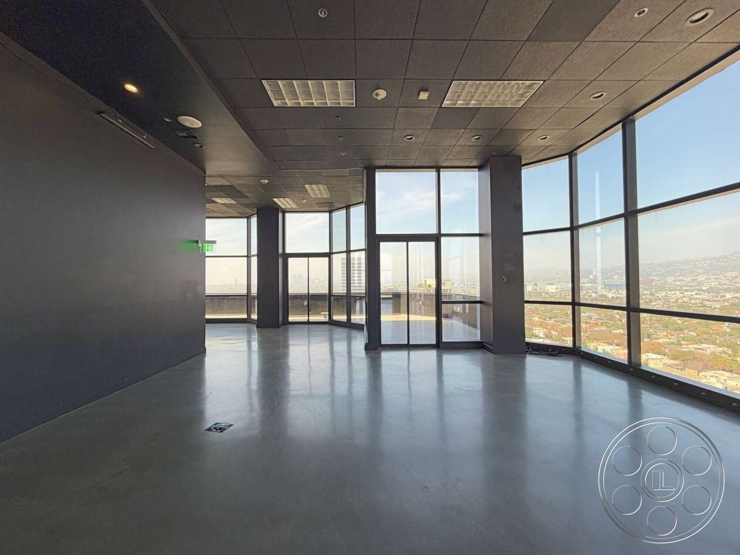 Wilshire Penthouse - open layout, polished concrete flooring, floor-to-ceiling windows, urban skyline view, modern office space, glass partition wall, black acoustic ceiling tiles