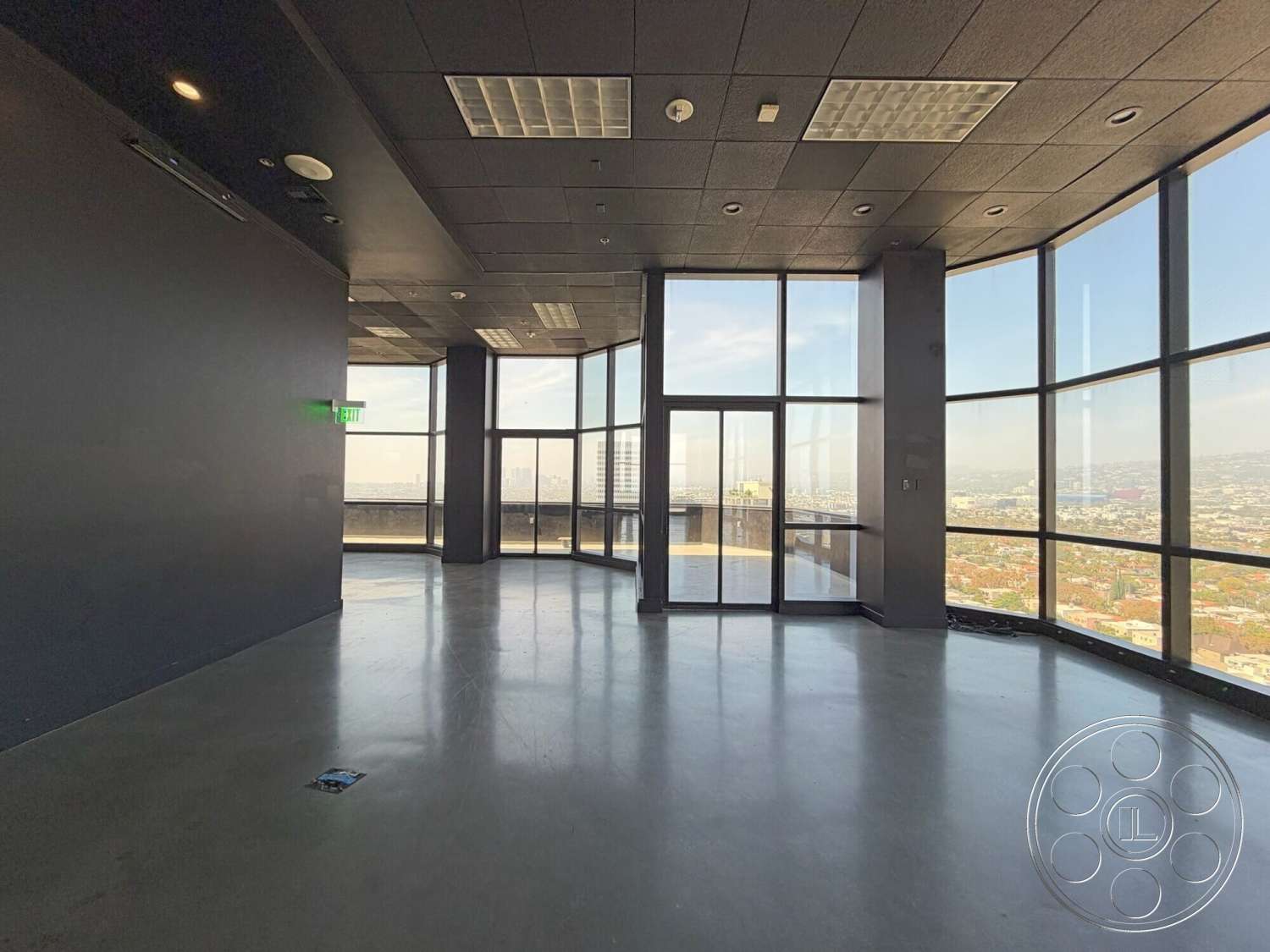Wilshire Penthouse - minimalist design, polished concrete flooring, floor-to-ceiling windows, city skyline view, dark painted walls, modern office space, exposed ceiling tiles