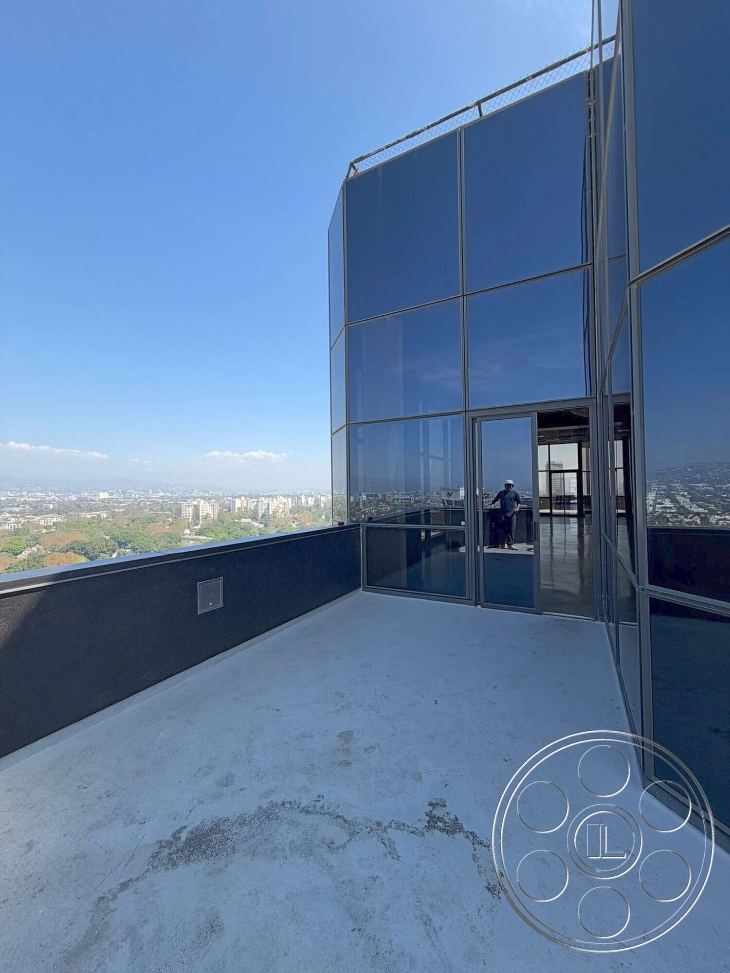 Wilshire Penthouse - modern design, concrete flooring, minimalist style, metal railing, floor-to-ceiling windows, industrial architecture, city skyline view, open-air terrace, high-rise building, exterior balcony, glass curtain wall