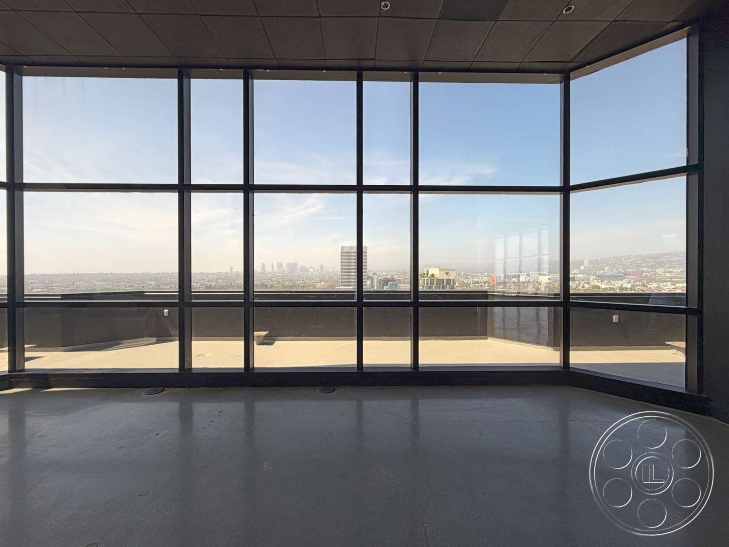 Wilshire Penthouse - minimalist design, open floor plan, concrete flooring, floor-to-ceiling windows, modern architectural style, city skyline view, black framed glass windows, industrial interior details