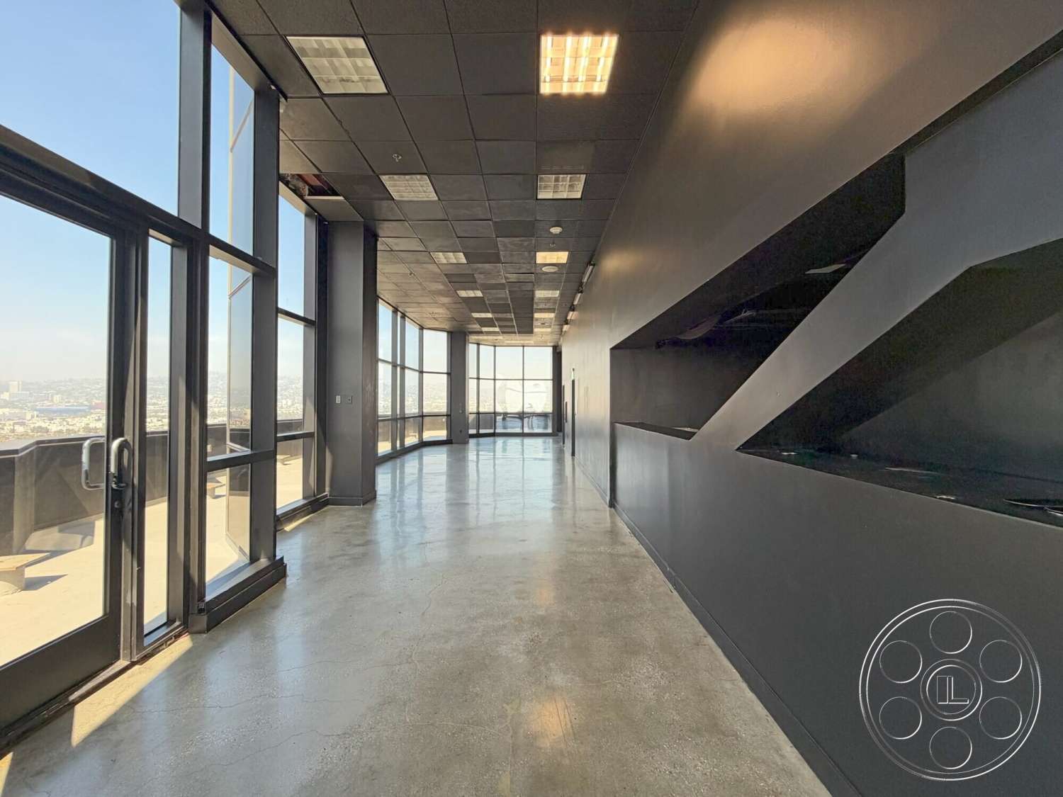 Wilshire Penthouse - floor-to-ceiling windows, geometric wall design, black painted walls, industrial ceiling tiles, exposed concrete flooring, modern open corridor