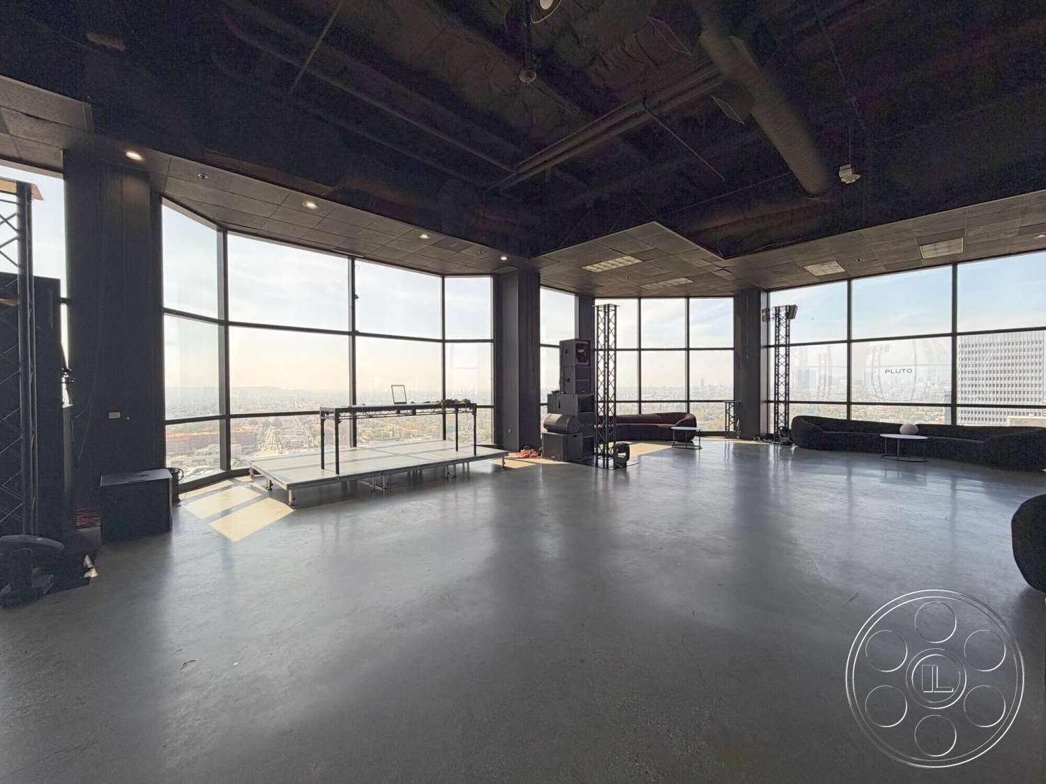 Wilshire Penthouse - modern furniture, concrete floor, open space layout, floor-to-ceiling windows, city skyline view, industrial style lighting, black acoustic panels, black suspended ceiling, performance stage area