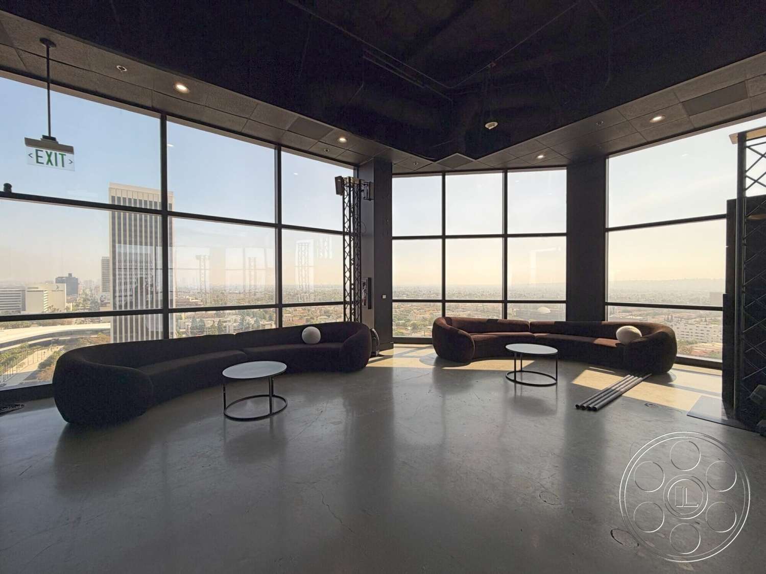 Wilshire Penthouse - concrete flooring, open space layout, minimalist design elements, floor-to-ceiling windows, urban skyline view, curved modern sofas, black ceiling treatment, round coffee tables