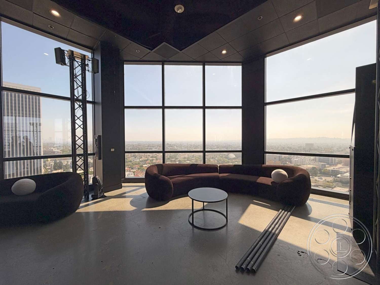 Wilshire Penthouse - minimalist design, concrete flooring, open space layout, modern coffee table, floor-to-ceiling windows, panoramic city view, curved sectional sofa, black ceiling panels