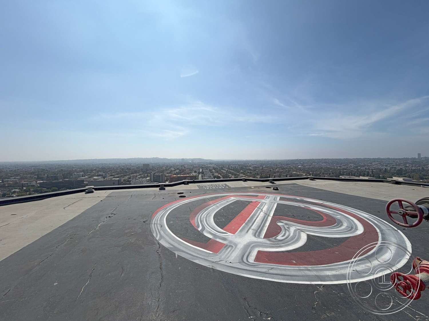 Wilshire Penthouse - exterior, urban skyline view, cityscape background, flat roof structure, concrete rooftop, industrial rooftop design, red and white painted design, prominent rooftop valves