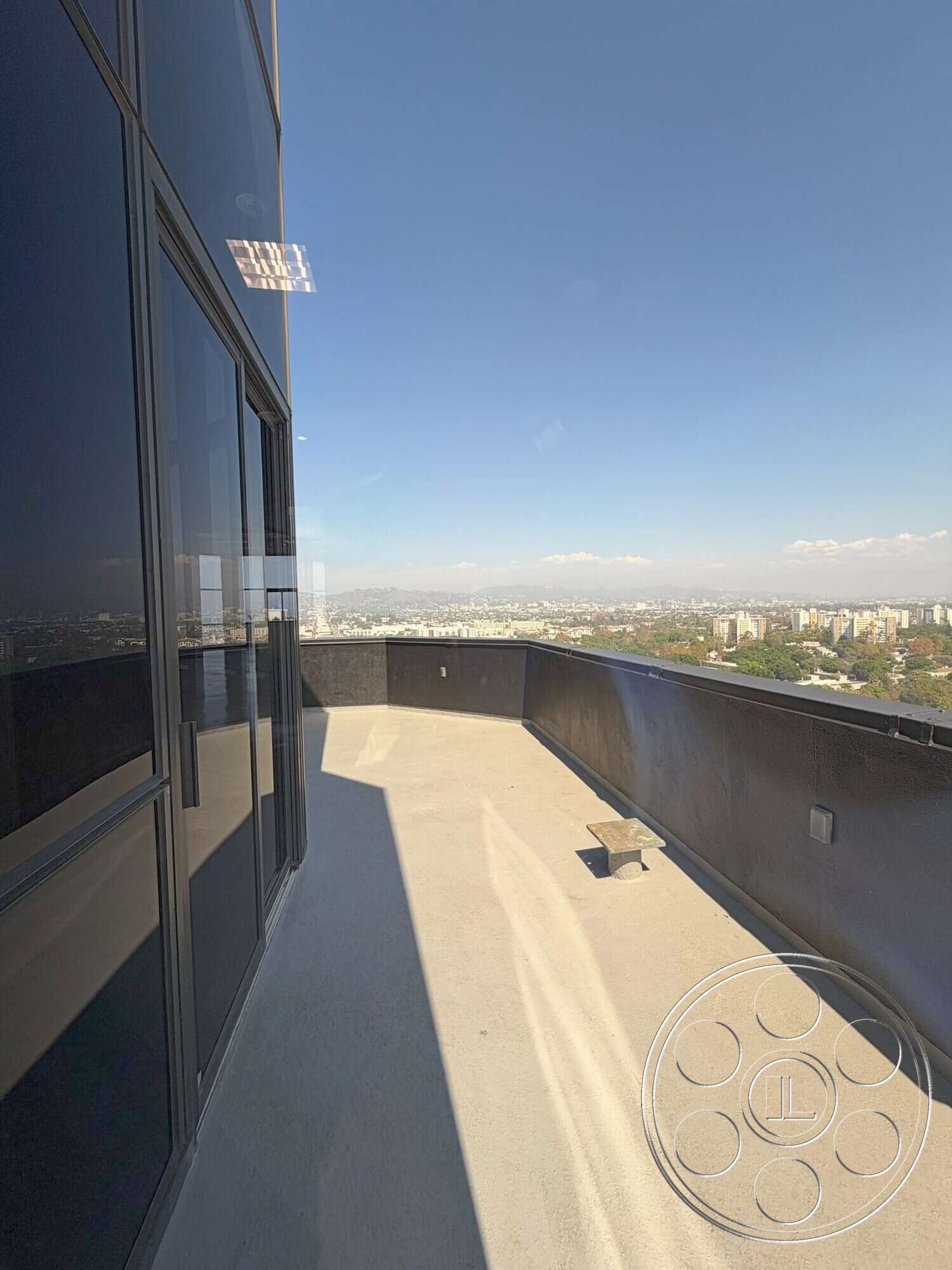 Wilshire Penthouse - exterior, flat roof, steel railing, city skyline view, modern architectural design, glass wall panels, concrete balcony flooring, curved balcony edge