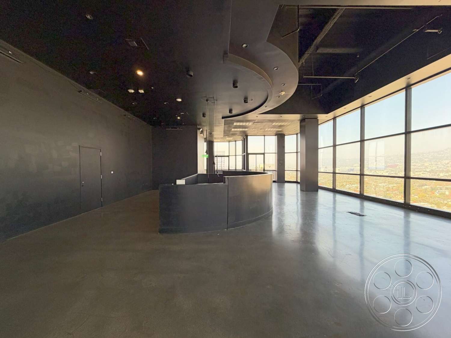 Wilshire Penthouse - polished concrete floor, open space layout, floor-to-ceiling windows, black painted walls, modern industrial design, high-rise city view, minimalist ceiling design, curved reception desk