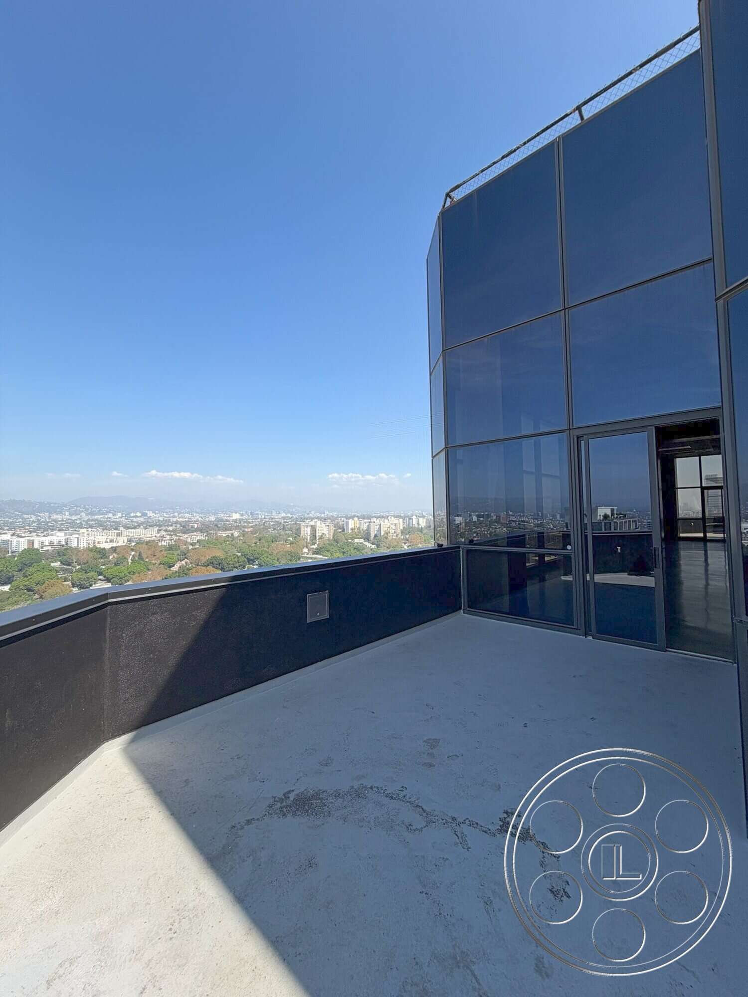 Wilshire Penthouse - exterior, metal railing, glass curtain wall, concrete building facade, concrete terrace floor, open city skyline view, angular balcony shape