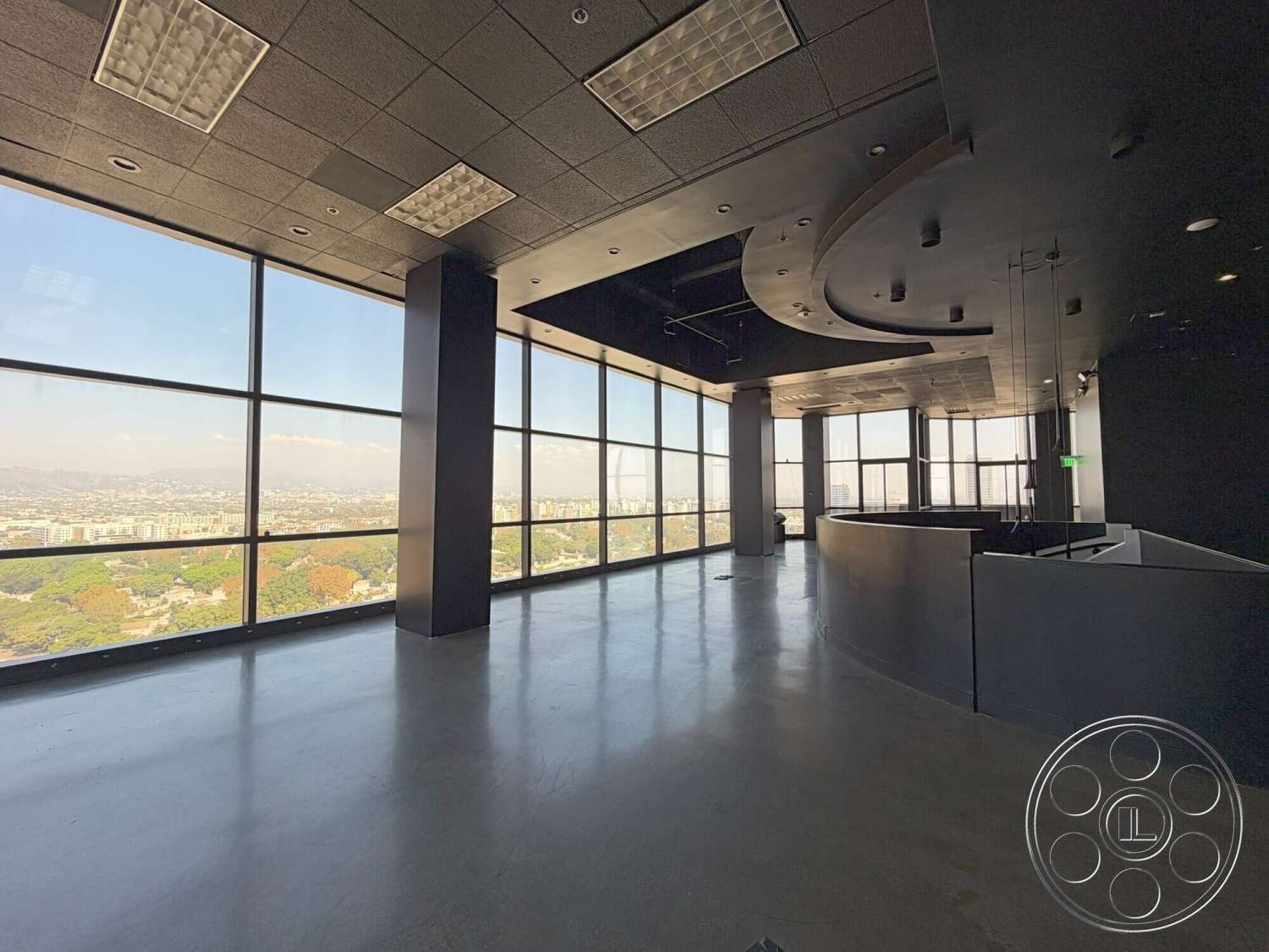 Wilshire Penthouse - minimalist design, open floor plan, polished concrete flooring, floor-to-ceiling windows, modern architectural style, urban skyline view, curved reception desk, textured drop ceiling