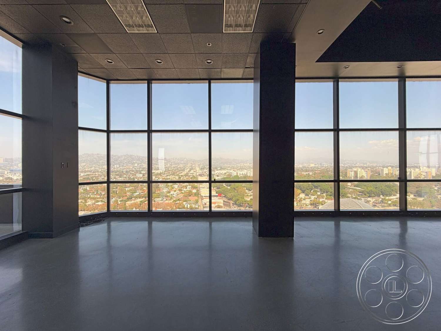 Wilshire Penthouse - natural light, minimalist design, open floor plan, concrete floors, floor-to-ceiling windows, urban skyline view, large glass panels, modern office space, black ceiling tiles